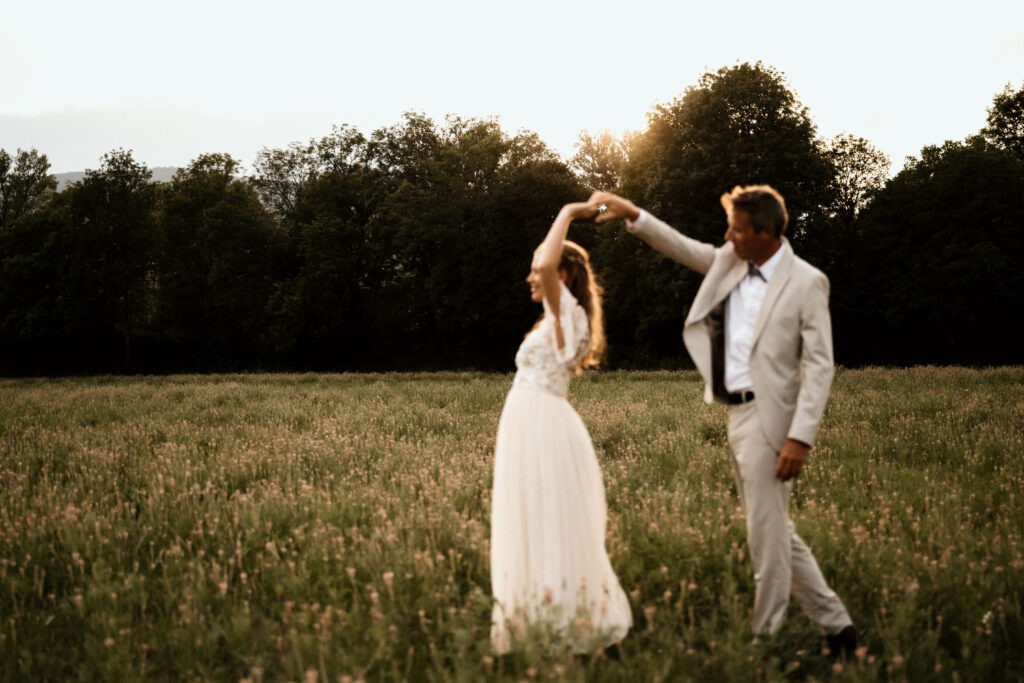 photographie par emilie schneider clerc studio semit dans la drome d'un couple marié qui danse dans les champs de fleurs sauvage au couché du soleil